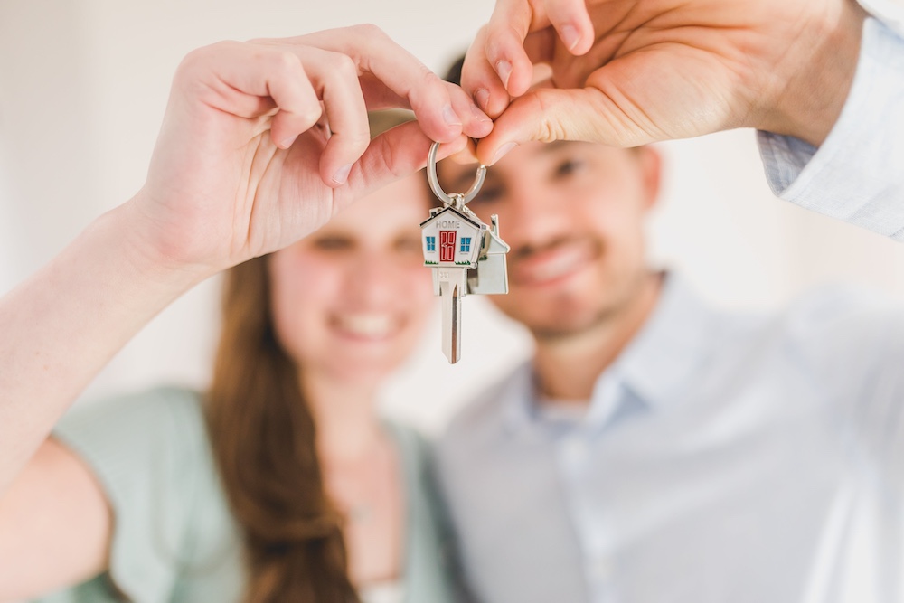 A couple smiling while holding up a pair of keys